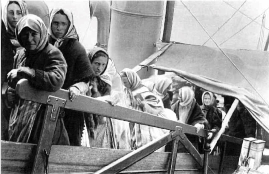 Auswandererinnen mit Kopftüchern an Deck eines Schiffs
